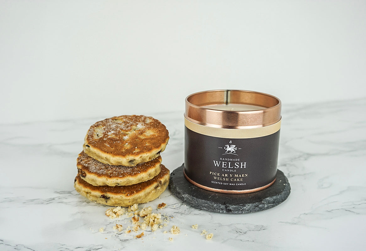 Handmade Welsh Candle labeled 'Handmade Welsh' next to a stack of Welsh cakes on a marble surface